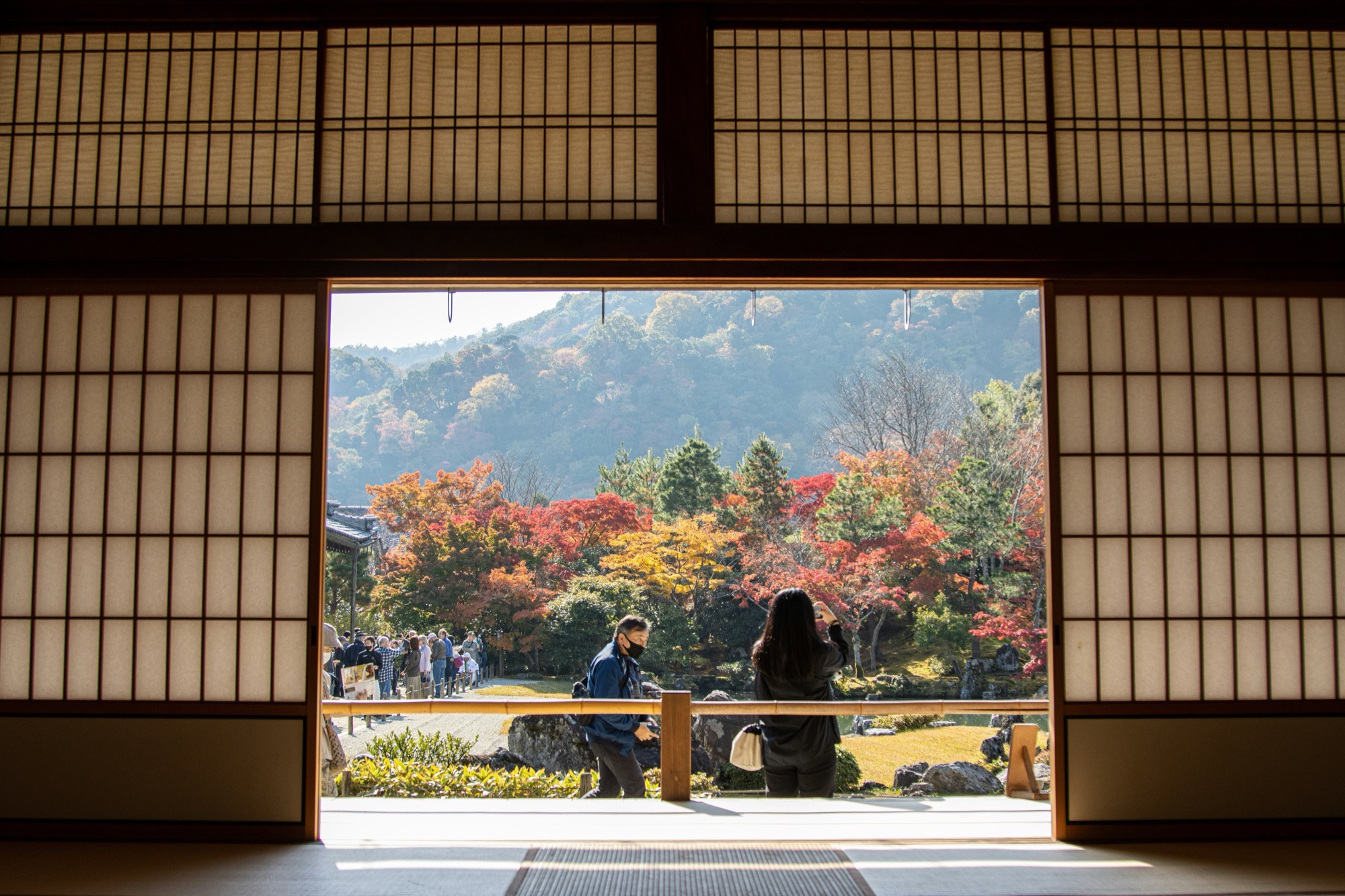 View through a traditional Japanese doorway to an autumn garden and mountains